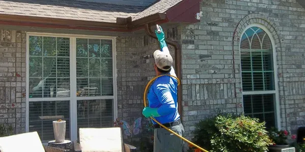 technician spraying exterior of home for pest protection